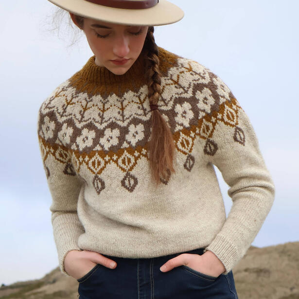 Young women wearing a hat and stranded colorwork hand knitted sweater with plant motifs in natural tones