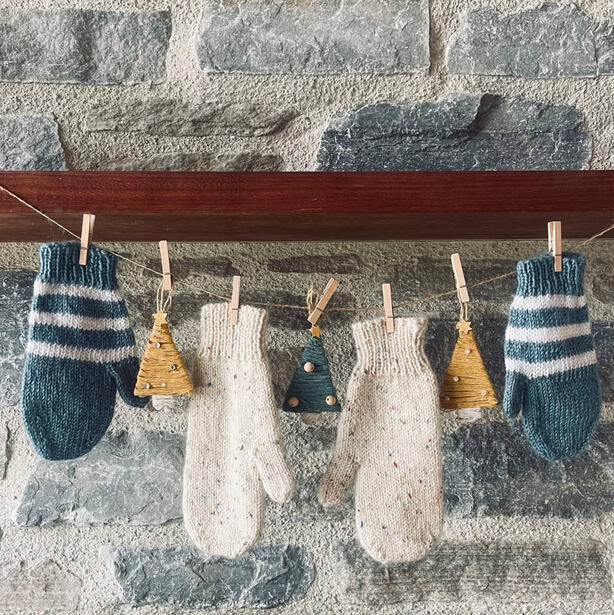 Two pairs of mittens hanging on a string with Christmas decorations