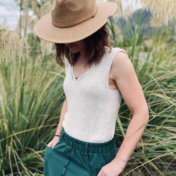 Women wearing a sleeveless knitted cotton top, green skirt and hat.