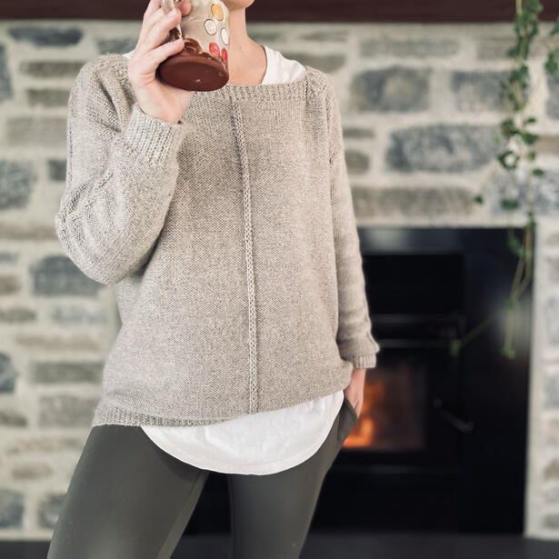 Women wearing alpaca knitted sweater with square neck and slip stitch details standing by fire